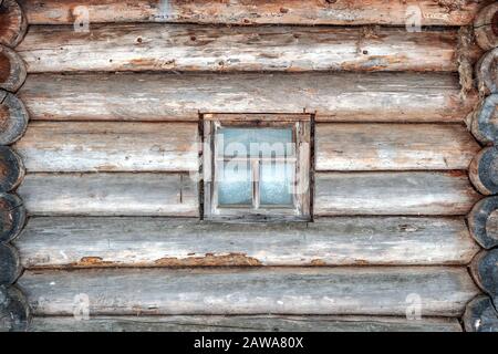 Log wall of an old wooden house with a window taken close-up, wooden architecture Stock Photo