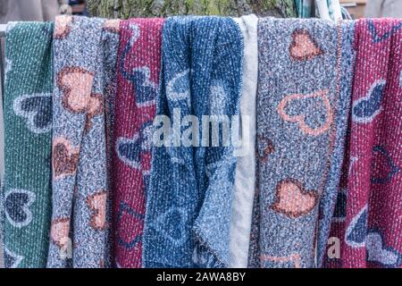 woven scarfs hanging on a bar in a shoppingstreet in the window with pied de poulle design with beautifull designs and colors Stock Photo