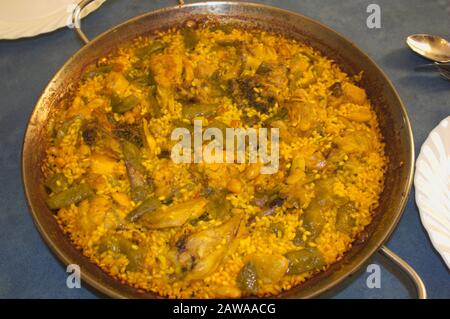 Close-up of a traditional Valencian paella on a table ready to be served on the plates to eat Stock Photo