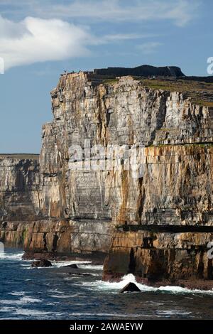 Tourist standing on the edge of the cliffs in Dun Aengus fort on Inishmore, largest of the Aran islands on the Wild Atlantic Way in Galway Ireland Stock Photo