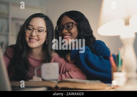 two women laugh looking at the laptop Stock Photo