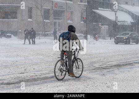 Montreal, CA, 7 February 2020: Man riding bike in Downtown Montreal during snow storm Stock Photo