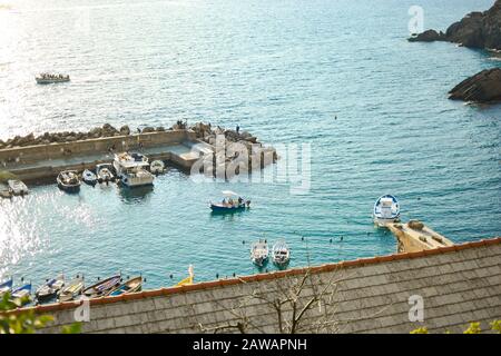 Aqua blue sea along the Ligurian coast of Italy at Cinque Terre, with colorful boats in the harbor near Vernazza, Italy Stock Photo