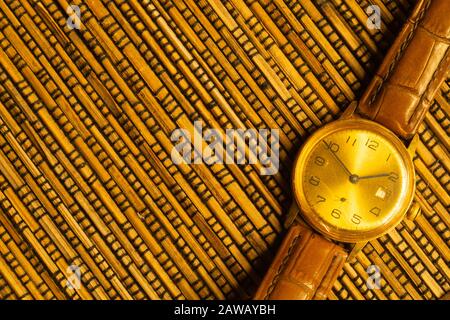 Vintage golden wristwatch with leather strap on the bamboo background. copy space Stock Photo