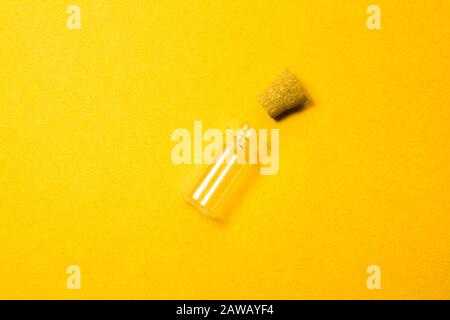 Empty little bottle with cork stopper isolated on yellow. glass vessel. transparent container. test tube Stock Photo