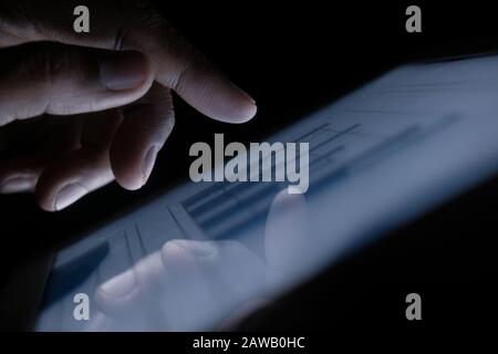 Man hand analyzing chart on digital table at night, close up Stock Photo
