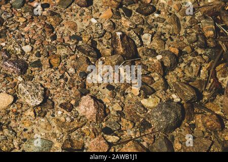 Shiny transparent water. clear water with pebbles and stone on the bottom. shining reflections of sun rays and ripples on the water surface Stock Photo