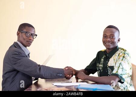 African student happily smiling and laughingwhilst shaking hands together as a diversity symbol in isolated studio Stock Photo