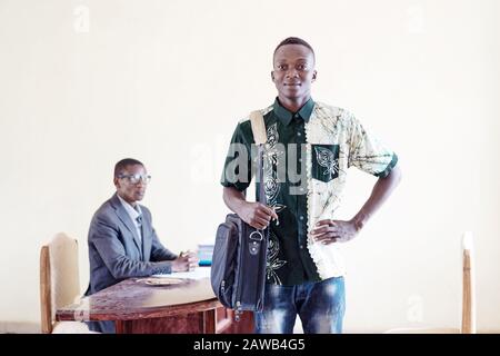 Proud African student with laptop bag posing in front of interviewer for a company in Africa Stock Photo