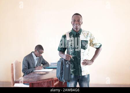 Beautiful image of African young student posing with laptop bag after successful job interview in company's office Stock Photo