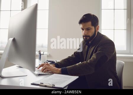 Businessman works at the computer at the table in the workplace in the office Stock Photo