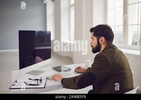 Businessman works at the computer at the table in the workplace in the office Stock Photo
