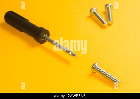Steel screw on a yellow background. working tools Stock Photo