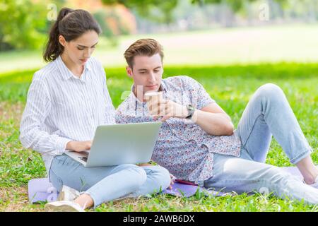 couple man and women teen working use laptop to working at outdoor park holiday Stock Photo