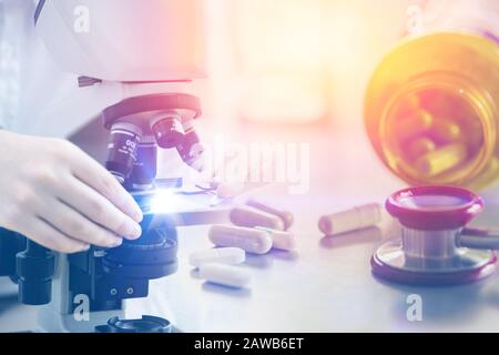 medicine pills with microscope in medical science research lab for pharmaceutical industry concept Stock Photo