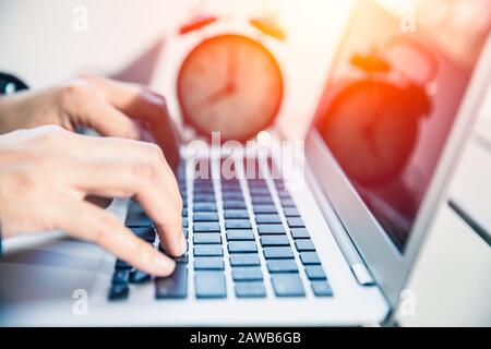 Closeup hand working on laptop computer outdoor with time clock for business work hours concept. Stock Photo