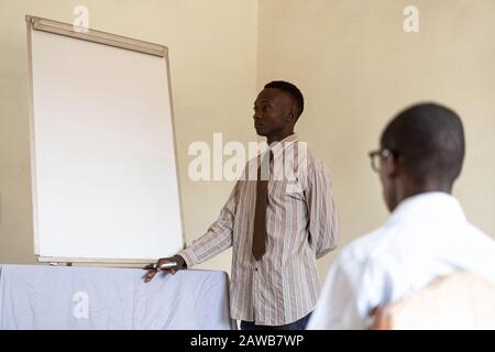 Black African Businessman standing in front of whiteboard with a striped shirt Stock Photo