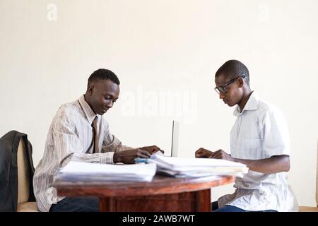 Two African Businessmen working on their Sheets in the studio in an African capital city Stock Photo