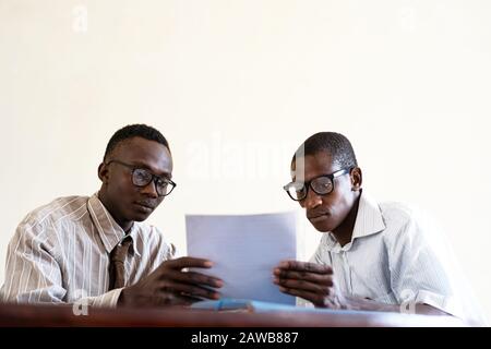 Two working African Business People with Glasses, Documents and Concentrating on their papers Stock Photo