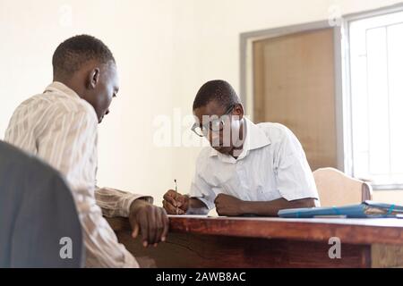 African employees working together in an office, signing papers and documents on desk Stock Photo