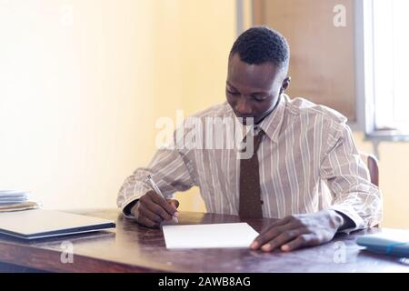 Young business man working in his office on documents with laptop on his desk in Bamako, Mali Stock Photo