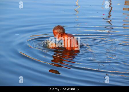 close-up of a old aged man bathing in the holy ganga river with blue clear water wave on morning time , the ganga river Stock Photo