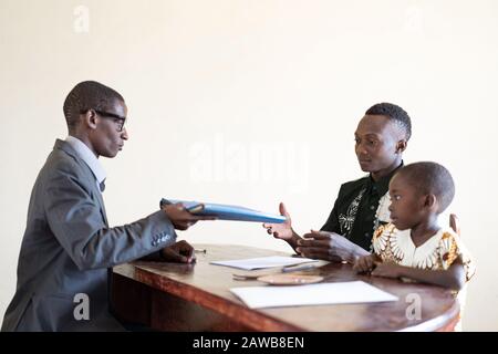 African dad and son in office getting documents about boy getting into school or adoption papers Stock Photo