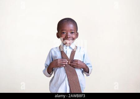 Happy African black boy posing in front of camera by smiling and laughing in front of isolated background Stock Photo