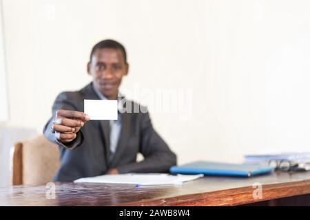Smiling cheerful young business man happily showing his business calling card with copy space and isolated on white background in his studio or office Stock Photo