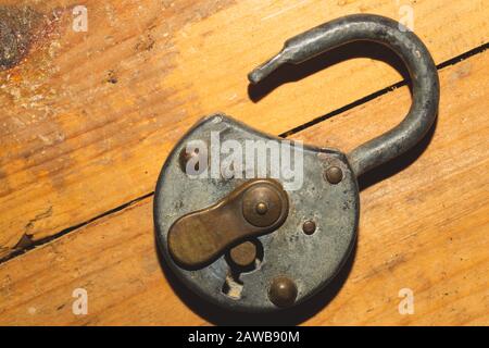 Old rusty lock on a wooden table. Vintage padlock on wood background Stock Photo