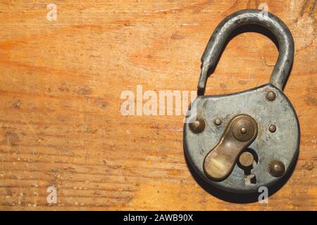 Old rusty lock on a wooden table. Vintage padlock on wood background Stock Photo