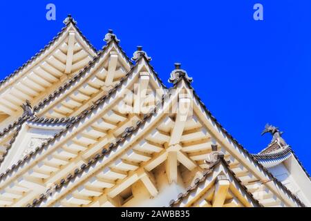 Traditional japanese architecture - corners of layered roof with beams and inner structure against blue sky in one of historic castles. Stock Photo