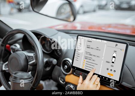 Woman controlling car with a digital dashboard switching autopilot mode, close-up on a touchscreen with launched program. Smart electric car concept Stock Photo