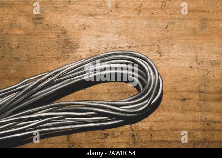Grey wire on a wood background. wire without braiding lies on the wooden table. work tool Stock Photo