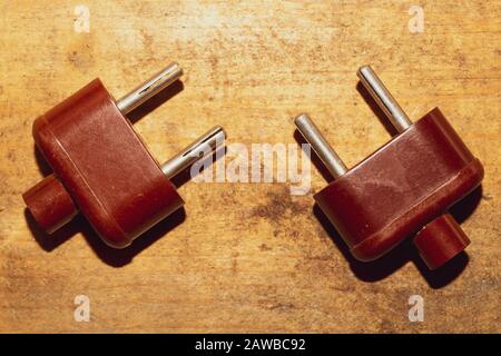 Two vintage brown power plugs without cord on the wooden table Stock Photo