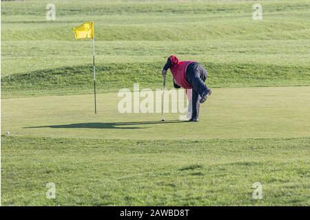 A golfer placing his ball on the green. Stock Photo