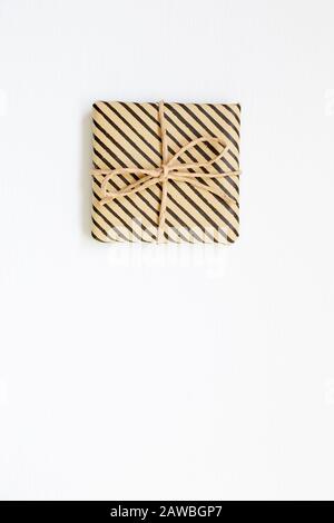 Gift box wrapped in striped kraft paper on white background Stock Photo