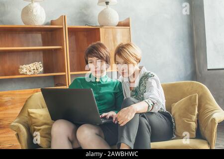 Mature women with laptop indoors (lady 40s and 60s years old) Stock Photo