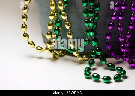 Close up abstract texture view of traditional three color Mardi Gras beads (purple, gold and green) draped over a small wooden bucket Stock Photo