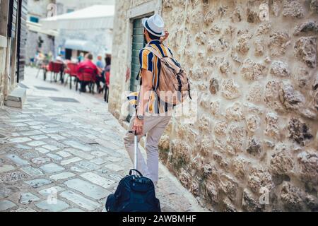 Handsome bearded tourist with backpack is making travel across city. Stock Photo