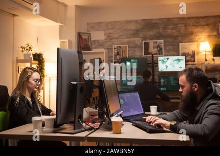Beautiful female hacker in working together with cyber criminals. Hacker team. Stock Photo