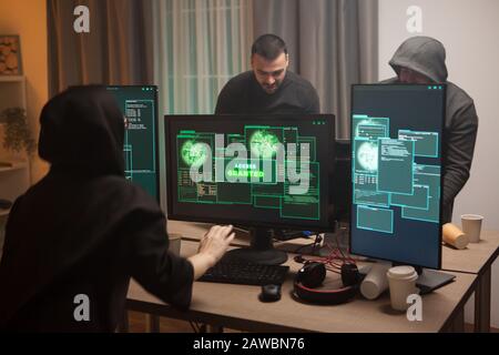 Excited female hacker after getting access granted after a cyber attack on a firewall. Team of hackers. Stock Photo
