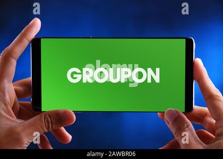 POZNAN, POL - JUL 10, 2019: Hands holding smartphone displaying logo of Groupon, an American worldwide e-commerce marketplace connecting subscribers w Stock Photo