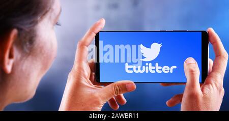 POZNAN, POL - JUL 10, 2019: Woman holding smartphone displaying logo of Twitter, an American online microblogging and social networking service Stock Photo