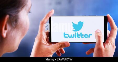 POZNAN, POL - JUL 10, 2019: Woman holding smartphone displaying logo of Twitter, an American online microblogging and social networking service Stock Photo