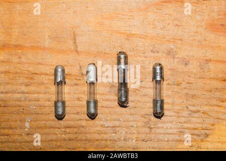 Row of fuses with burned out fuse on wooden background. safety device for overcurrent protection. protection of an electrical circuit Stock Photo