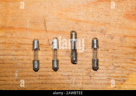 Row of fuses with burned out fuse on wooden background. safety device for overcurrent protection. protection of an electrical circuit Stock Photo