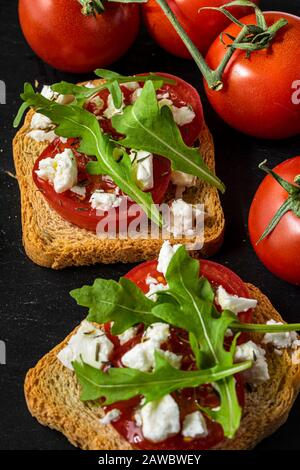 Small toasts with tomatoes and Feta cheese. Stock Photo