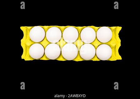 Chicken eggs in a yellow container on a black background. Contemporary art, concept Stock Photo
