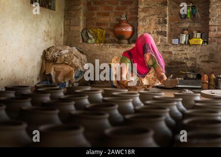 Woman in traditional colorful clothes kneads wet clay in readiness for the potter in village in Bundi, Rajasthan, India. Stock Photo